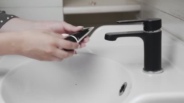 妇女站在浴室时，将黑胶刷子或黑色面罩捏在她张开的手掌上 — 图库视频影像