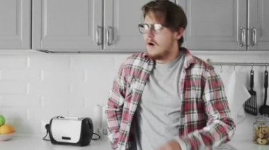 Evdeki mutfakta yorgun ve uykulu genç adamın portresi. Esniyor ve pencereye bakıyor.