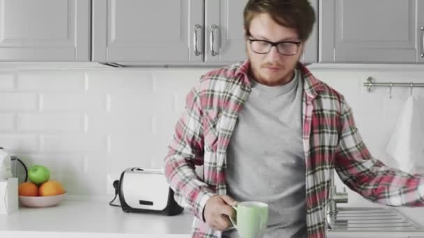 Young man making tea in the kitchen using kettle tipper — Stock Video