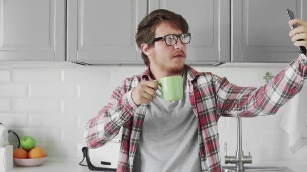 Young man taking selfie with geen cup in kitchen — Stock Video