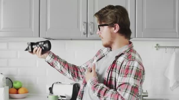 Mladý atraktivní muž blogger v ležérní oblečení natáčení videa na kameru v moderní kuchyni — Stock video