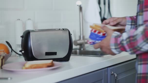 Чоловік кладе хліб у тостер. Хліб смажений. Готується сніданок. Електроприлад на кухні — стокове відео