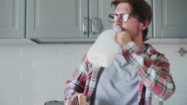 Genç adam çikolata ezmesiyle tost yiyor ve plastik şişeden süt içiyor.