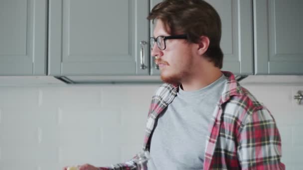 Junger Mann isst Toast mit Erdbeermarmelade und trinkt Orangensaft — Stockvideo
