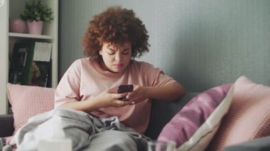 Hasta Afrikalı Amerikalı kız evdeki kanepede grip virüsü taşıyor. Doktoruna mesaj yazıyor ya da internetten hastalığın belirtilerini araştırıyor.