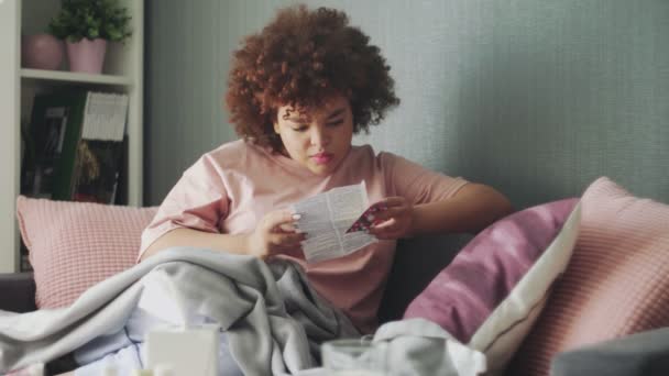 Sick african american girl is reading medication instructions — Stock Video