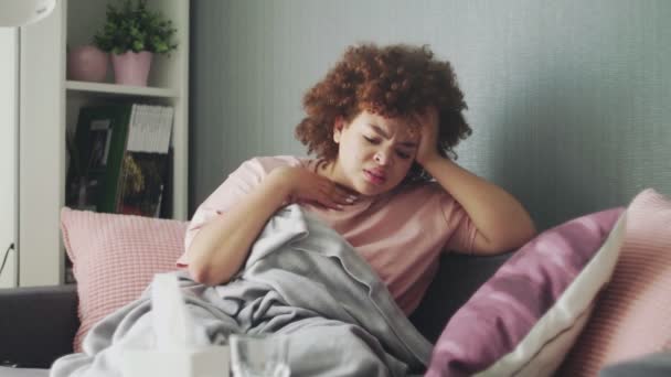 Young african american girl suffering from cough and sore throat wrapping body in blanket at home — Stock Video