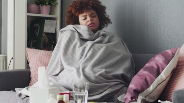 Covered with grey plaid young african american girl freezing feeling cold at home, ill sick girl having fever flu influenza temperature symptoms — Stock Video