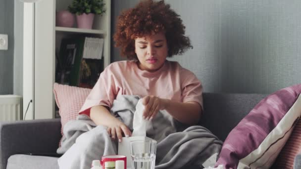 Niña afroamericana enferma con el virus de la gripe en el sofá en casa. Usa toallitas para estornudar. — Vídeo de stock