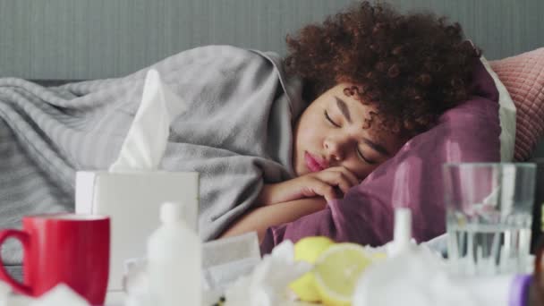 Enfermo joven afroamericano chica está durmiendo relajante durante la enfermedad tumbado en el sofá en el apartamento bajo cuadros calientes . — Vídeo de stock