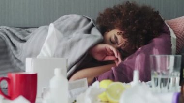 Hasta Afrikalı genç Amerikalı kız, hastalık sırasında uyuyor. Evdeki kanepede, sıcak ekosenin altında dinleniyor..