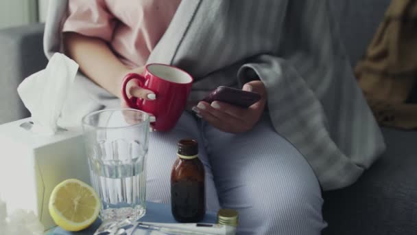 Gros plan de malade Jeune fille afro-américaine utilisant le téléphone et boire un thé chaud à la maison — Video