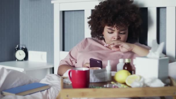 Nemocný mladý africký americký dívka pomocí telefonu v posteli doma — Stock video