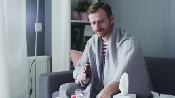 Sick man pouring medication or antipyretic syrup to spoon and drinking it — Stock Video