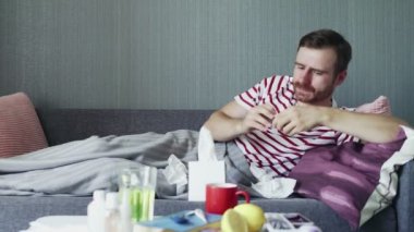 Yetişkin hasta bir adam kanepede yatar ve hastalık için reçeteli ilaç alır..