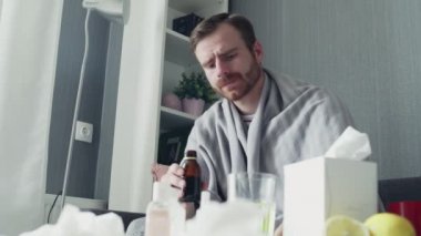 Hasta bir adam kaşıkla içmek için ilaç ya da antipiretik şurup döküyor.