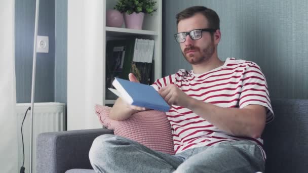 Vit ung snygg man med glasögon läser en bok — Stockvideo