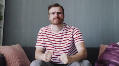 Genç adam evde TV 'de korku videosu ya da film izliyor. Korkmuş görünüyor.