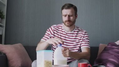 Sakallı adam kahvaltıyı hazırlamak için bardağa süt döker.