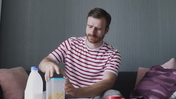 Bearded man pours cork flakes into a cup to preparing breakfast — Stock Video