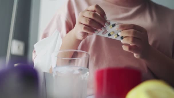 Nahaufnahme eines kranken afrikanisch-amerikanischen Mädchens nimmt Tabletten mit Wasser, liegend auf der Couch. — Stockvideo