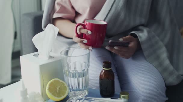 Közelkép a beteg fiatal afro-amerikai lány telefonál és forró teát iszik otthon — Stock videók