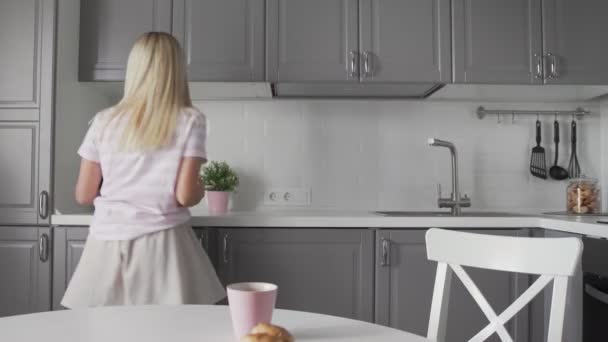 Mladá vzrušená žena drží smartphone a tanec v kuchyni. — Stock video