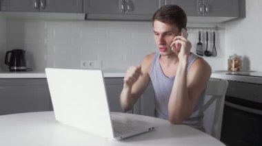 Freelancer telefonda konuşuyor ve mutfakta defter üzerinde çalışıyor..