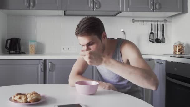 Genç adam çorba içiyor ve mutfakta telefon kullanıyor. — Stok video