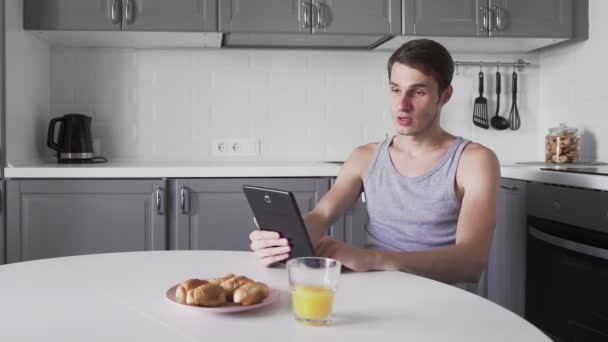 Adam mutfakta tablet bilgisayarında sohbet ediyor. — Stok video