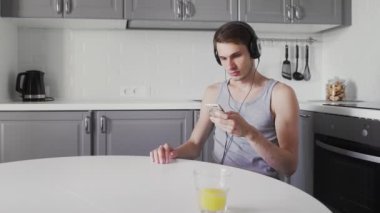 Genç adam masada oturuyor ve kulaklıkla müzik dinliyor.