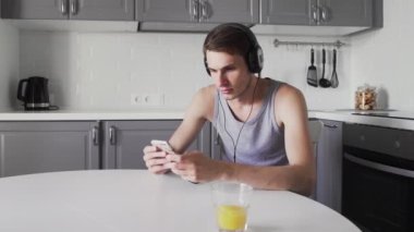 Genç adam masada oturuyor ve kulaklıkla müzik dinliyor.