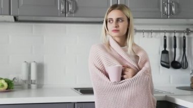 Battaniyeli tatlı kız çay içiyor ve sabahları pencereden dışarı bakıyor.