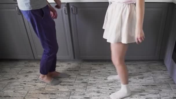 Низкий угол съемки привлекательная молодая радостная пара весело танцуют во время приготовления пищи на кухне дома — стоковое видео