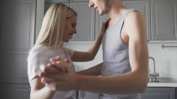 Atraente jovem casal alegre tem dança romântica enquanto cozinha na cozinha em casa — Vídeo de Stock