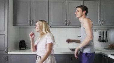 Evdeki mutfakta birlikte gülüp, eğlenip, dans eden eğlenceli genç insanlar.