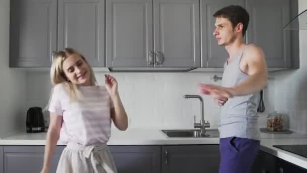 Νεαρό δημιουργικό hipster ζευγάρι χορεύουν μαζί στην κουζίνα στο σπίτι. Φανταχτερά αστείοι νέοι άνθρωποι είναι ανόητοι και απολαμβάνουν μαζί — Αρχείο Βίντεο