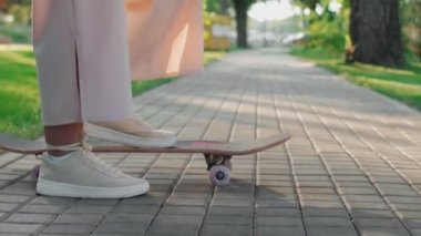 Kaykaycı elinde kaykayla durur ve onu iterdi.