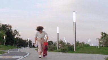 Genç profesyonel bayan kaykaycı parkta kaykay yapıyor.
