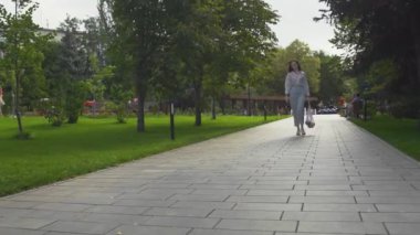 Kadın elinde sebzelerle pamuk ağıyla alışveriş çantası tutuyor ve yaz parkında yürüyor.