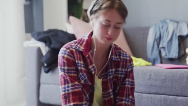 Портрет женщины в наушниках очищает пол в гостиной — стоковое видео