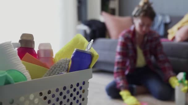 Cesta cheia de esponjas e produtos químicos domésticos com mulher em fundo embaçado — Vídeo de Stock