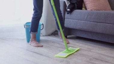 Kadın paspasla yerleri yıkıyor ve evde dans ediyor.