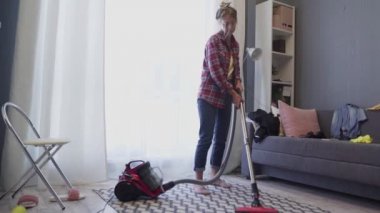 Kadın, oturma odasındaki halıyı temizlemek için her gün elektrikli süpürge kullanıyor..