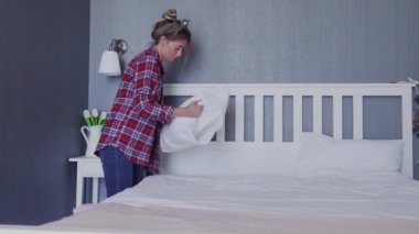 Yatak odasındaki yatağı genç kadın yapıyor.
