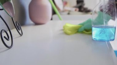 Masadan toz kaldırmak için sarı bez kullanan genç bir kadın.