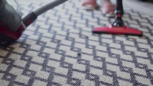Jonge vrouw met behulp van een stofzuiger om het tapijt te reinigen — Stockvideo