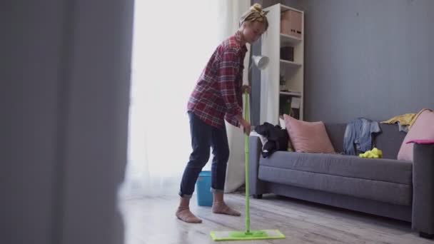 Mooie jonge vrouw schoonmaken vloer met dweil. — Stockvideo