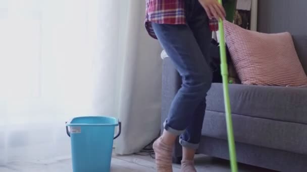 Слайд-снимок женщины, моющей пол шваброй и танцующей дома — стоковое видео