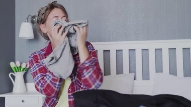 Schöne junge Frau sortiert saubere Kleidung auf dem Bett — Stockvideo